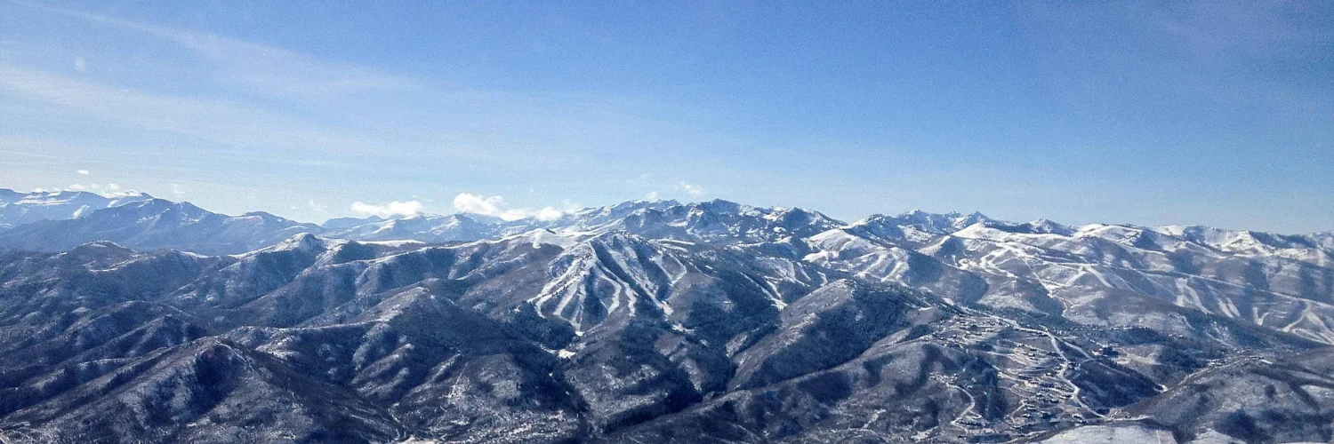 A scenic aerial view of Deer Valley, showcasing its expansive ski trails and rugged mountain terrain in Park City, Utah.