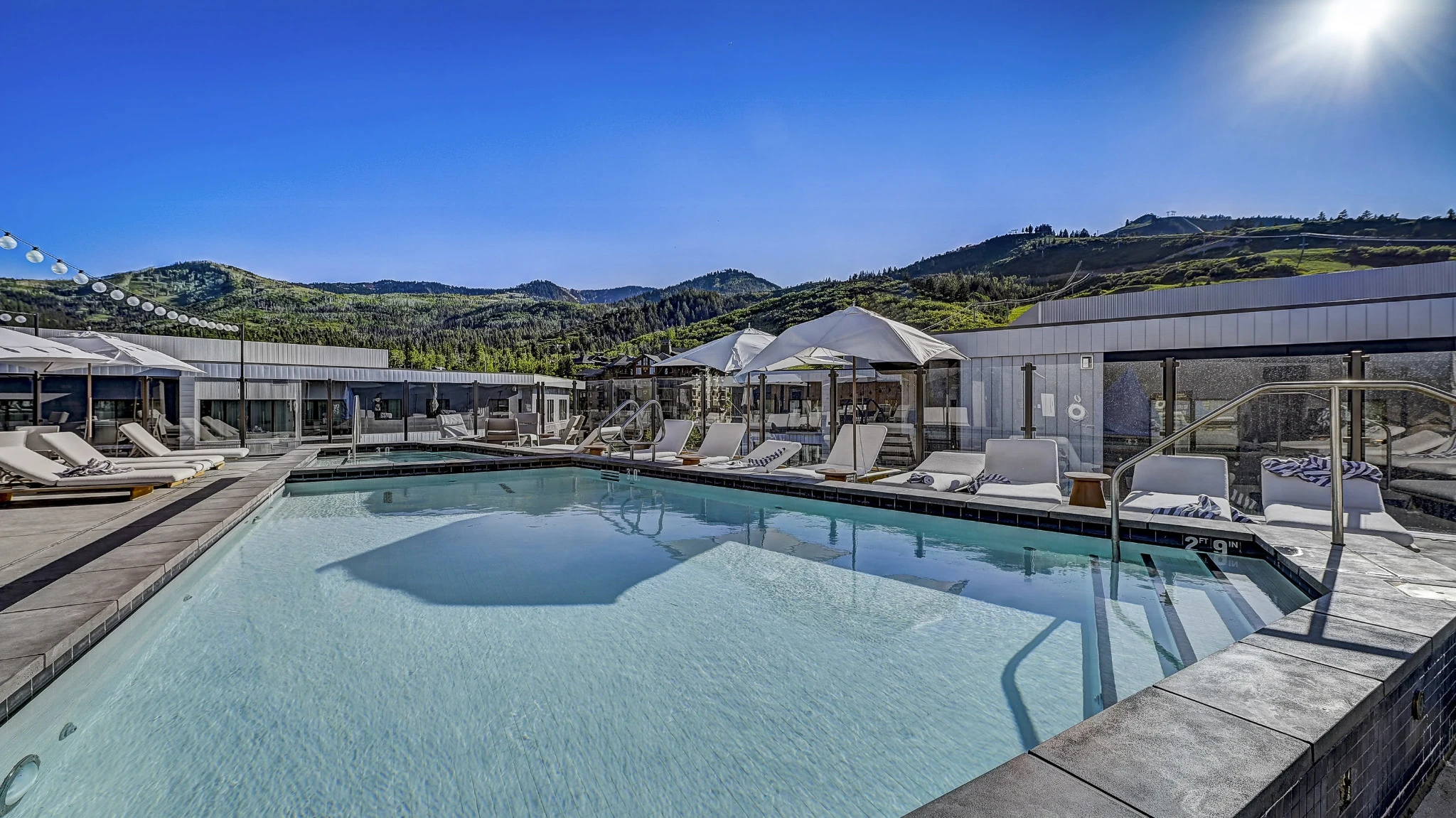 Luxury swimming pool at a Park City resort with mountain views and lounge chairs, showcasing Park City homes and condos with pools near Deer Valley and Canyons Village.