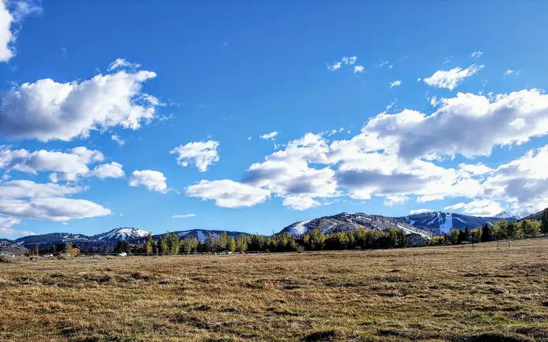 Open meadow near Aspen Springs Ranch in Park City, Utah, with snow-covered ski slopes and Iron Mountain visible to the north