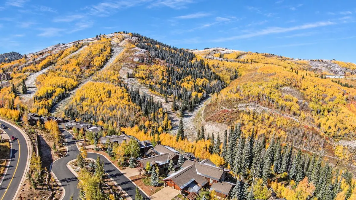 Homes below Deer Valley Resort ski runs in Park City, Utah, with fall aspens across the mountainside