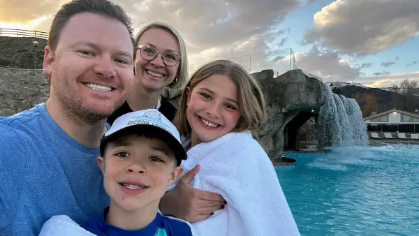 Derrik Carlson and family enjoying the outdoor resort pool at Homestead Residences in Midway, Utah, with mountain surroundings and on-site amenities visible.