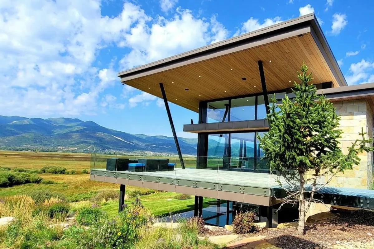 Contemporary custom home on Old Ranch Road in Park City Utah with cantilevered glass deck overlooking open meadow and Wasatch mountain backdrop