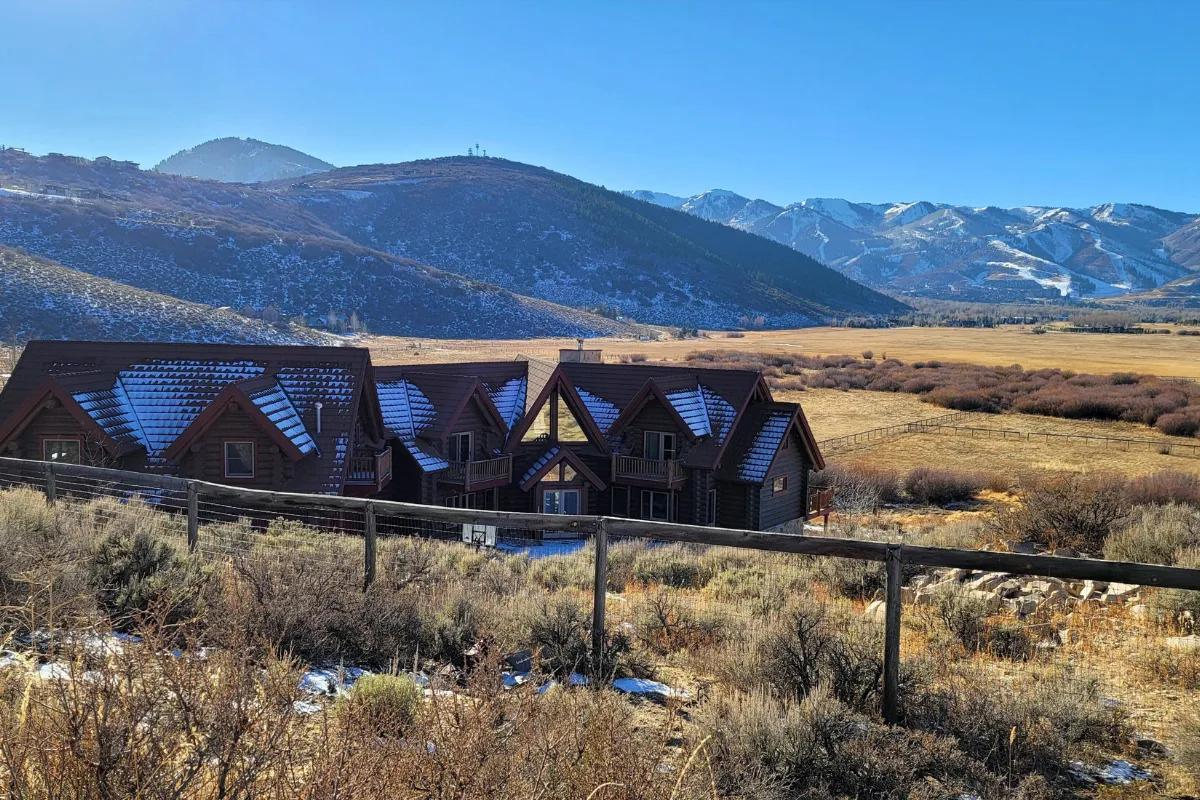 Log and timber estate home on Old Ranch Road near Park City Utah with ranch fence, open sagebrush pasture, and Wasatch mountain ski resort views