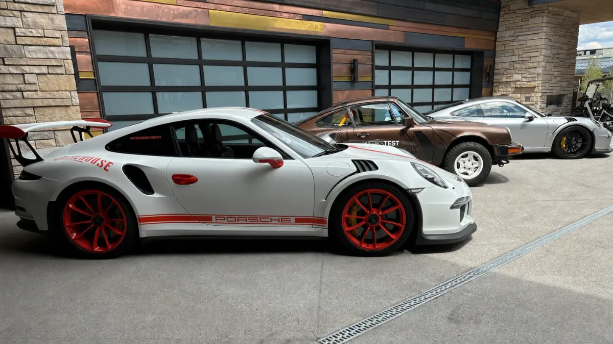 Three Porsche vehicles parked outside a Park City home with a three-car garage